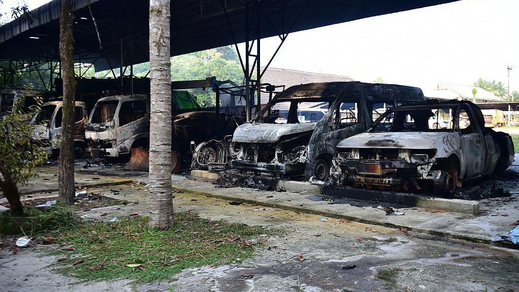 Image caption,Charred vehicles pictured outside an administrative office in Narathiwat