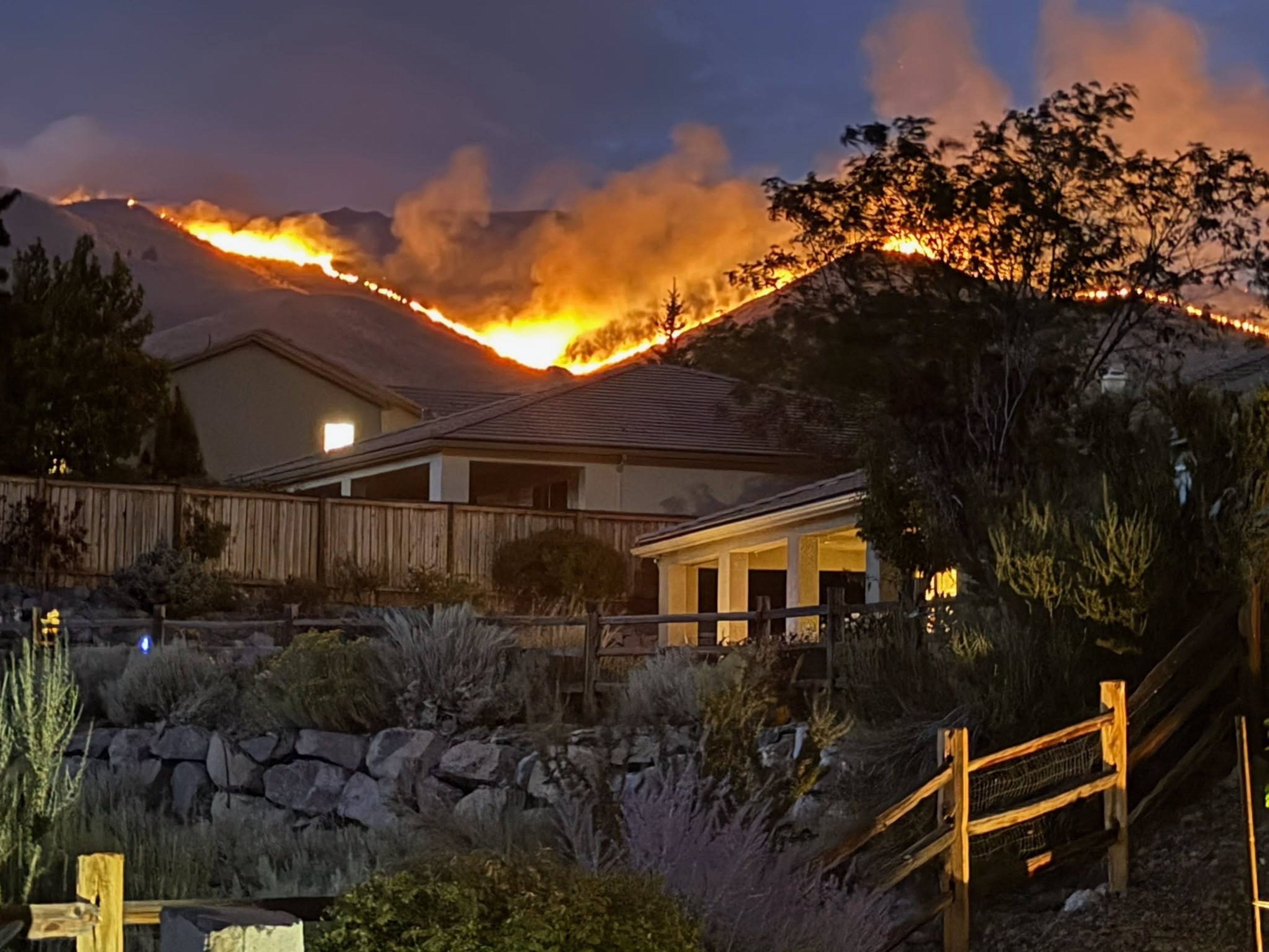 Residents look over a fence at the Hawk Fire burning, August 23, 2026, near Reno, Nevada.Trevor Bexon/Getty Images