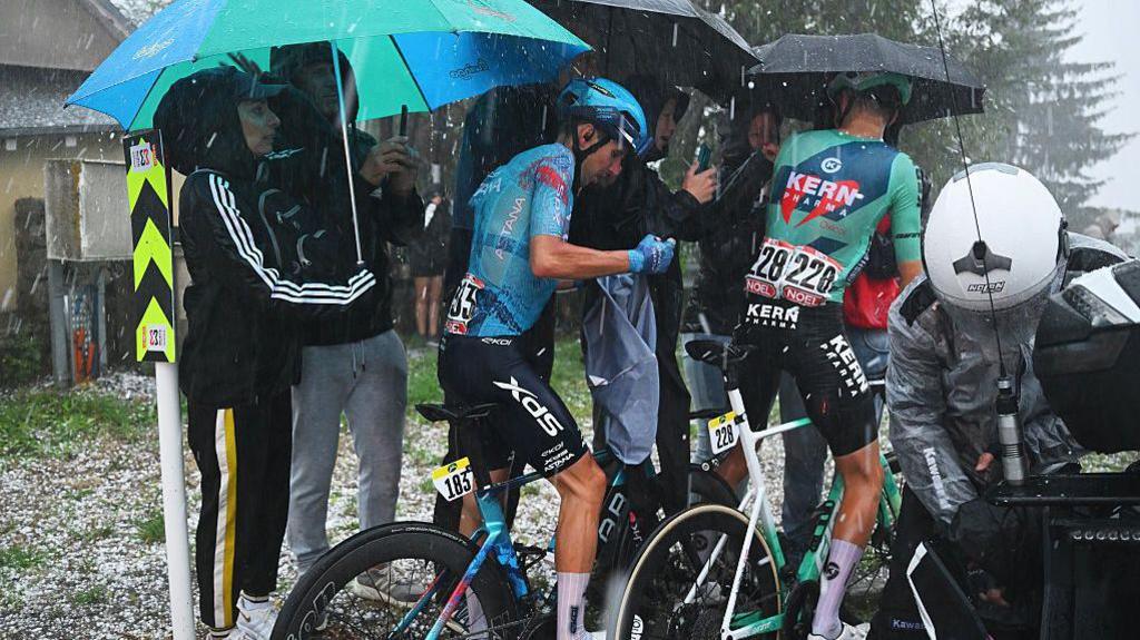 Image caption,Cyclists in the Vuelta a España race had to seek shelter in a hotel when they were hit by a hailstorm