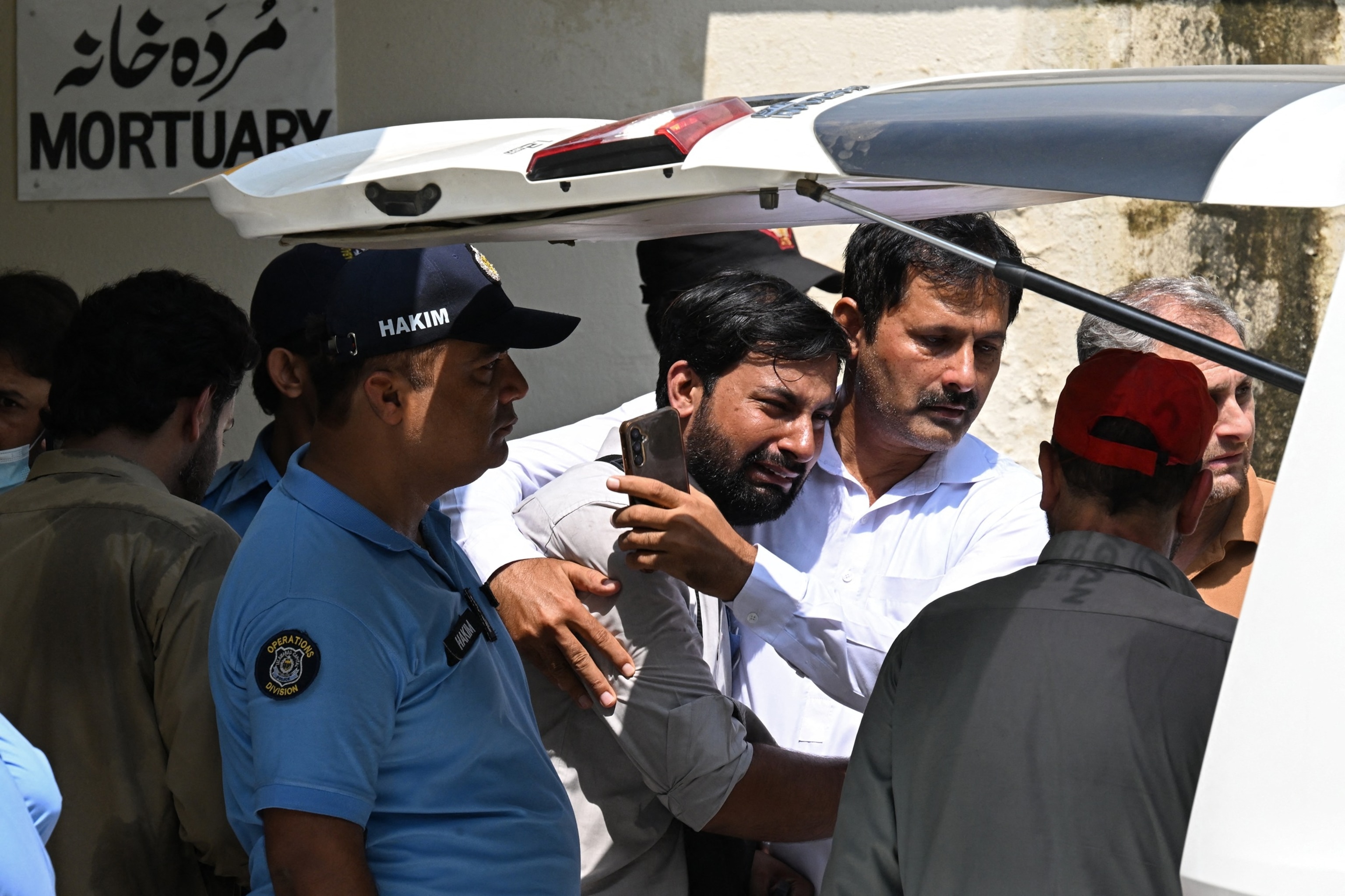 TOPSHOT - A man consoles a grieving father (C) as his child's coffin is carried after a fire outside the Mother and Child Health (MCH) ward at the Pakistan Institute of Medical Sciences (PIMS) Hospital in Islamabad on August 26, 2026. A fire erupted in a hospital maternity ward in Islamabad on August 26 killing 14 infants, Pakistan authorities said, blaming a faulty air conditioner for the blaze.Aamir Qureshi/AFP via Getty Images
