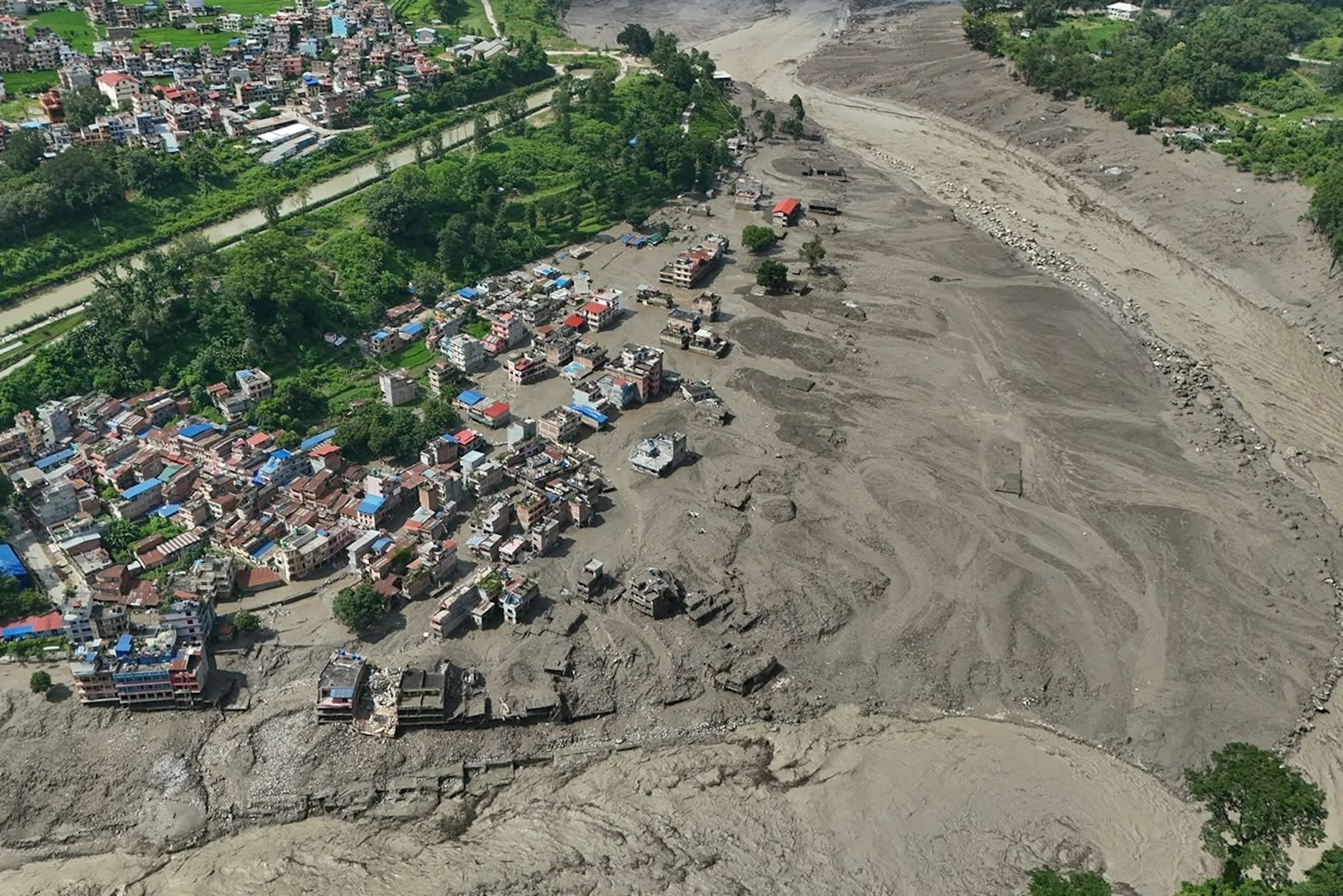 Damaged houses stand precariously near the swollen, debris-choked banks of the Trishuli River after flash floods in Nepal's Nuwakot district, Aug. 26, 2026.Niranjan Shrestha/AP Photo