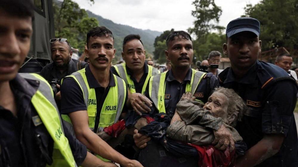 Image caption,Police officers were pictured carrying a survivor from the flash floods in Nepal's Nuwakot district