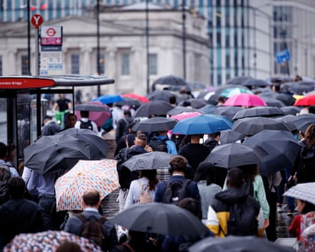 Commuters holding umbrellas cross London Bridge.Photograph: Tolga Akmen/EPA