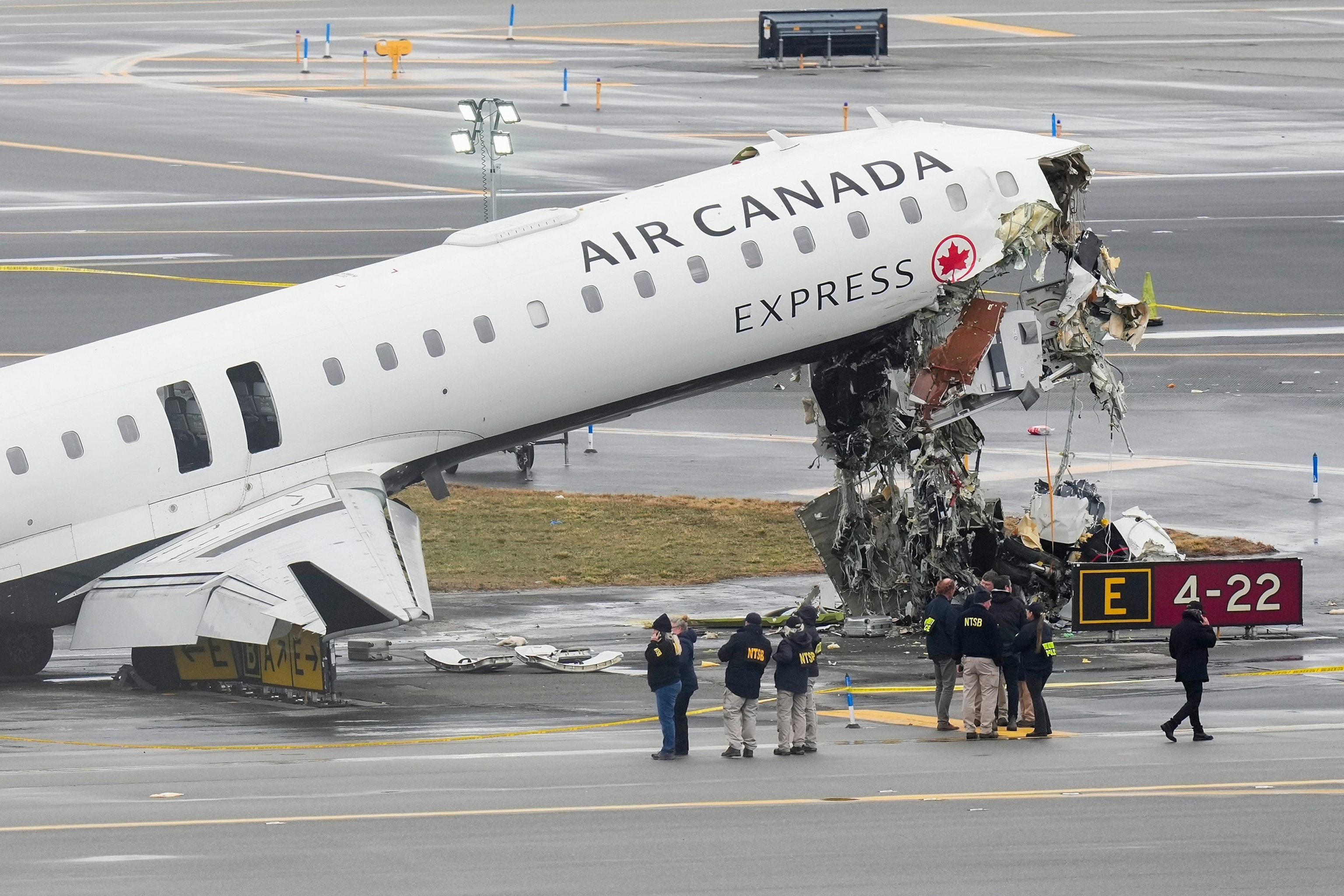 Officials with the National Transportation Safety Board investigate the site on March 23, 2026, where an Air Canada jet came to rest after colliding with a Port Authority firetruck at LaGuardia Airport, shortly after landing in New York.Seth Wenig/AP
