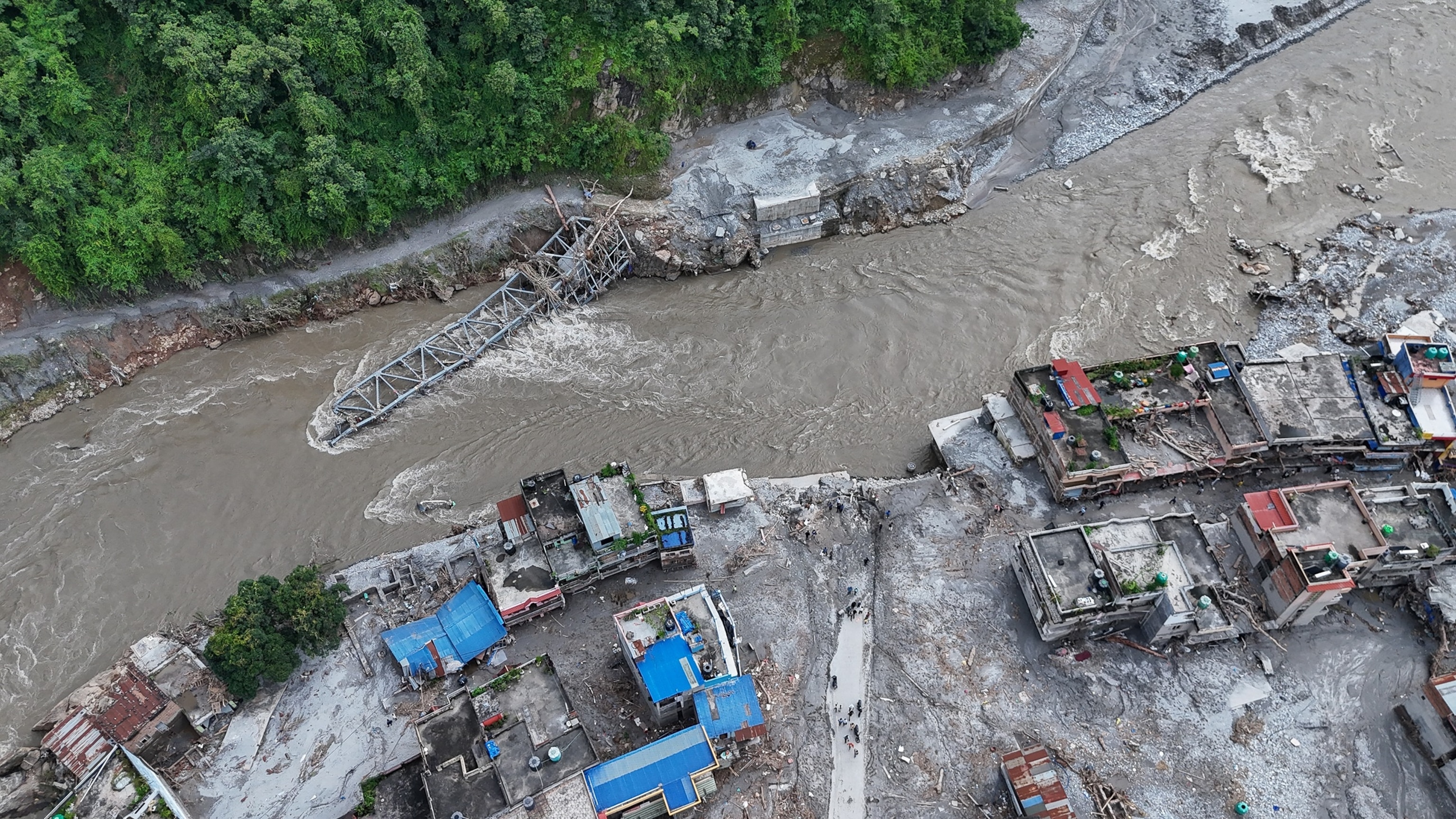 A collapsed bridge and damaged settlements debris and mud covers an area following flash floods, August 28, 2026 in DeviGhat village, Nepal.Ritesh Shukla/Getty Images