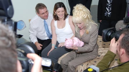 Shane Jarman and his wife, Claire, watch as Dolly Parton holds newborn Emma.Photograph: The Rotherham NHS Foundation Trust