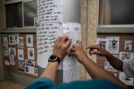 Relatives search through lists of people reported missing outside the hospital in Kathmandu.Photograph: Ahmer Khan/The Guardian