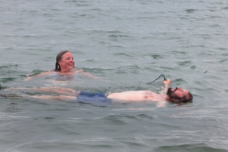 Anna Field and her husband, Jim, take the plunge in Brighton. Field checks for sewage spills before she goes for a swim.Photograph: Martin Godwin/The Guardian