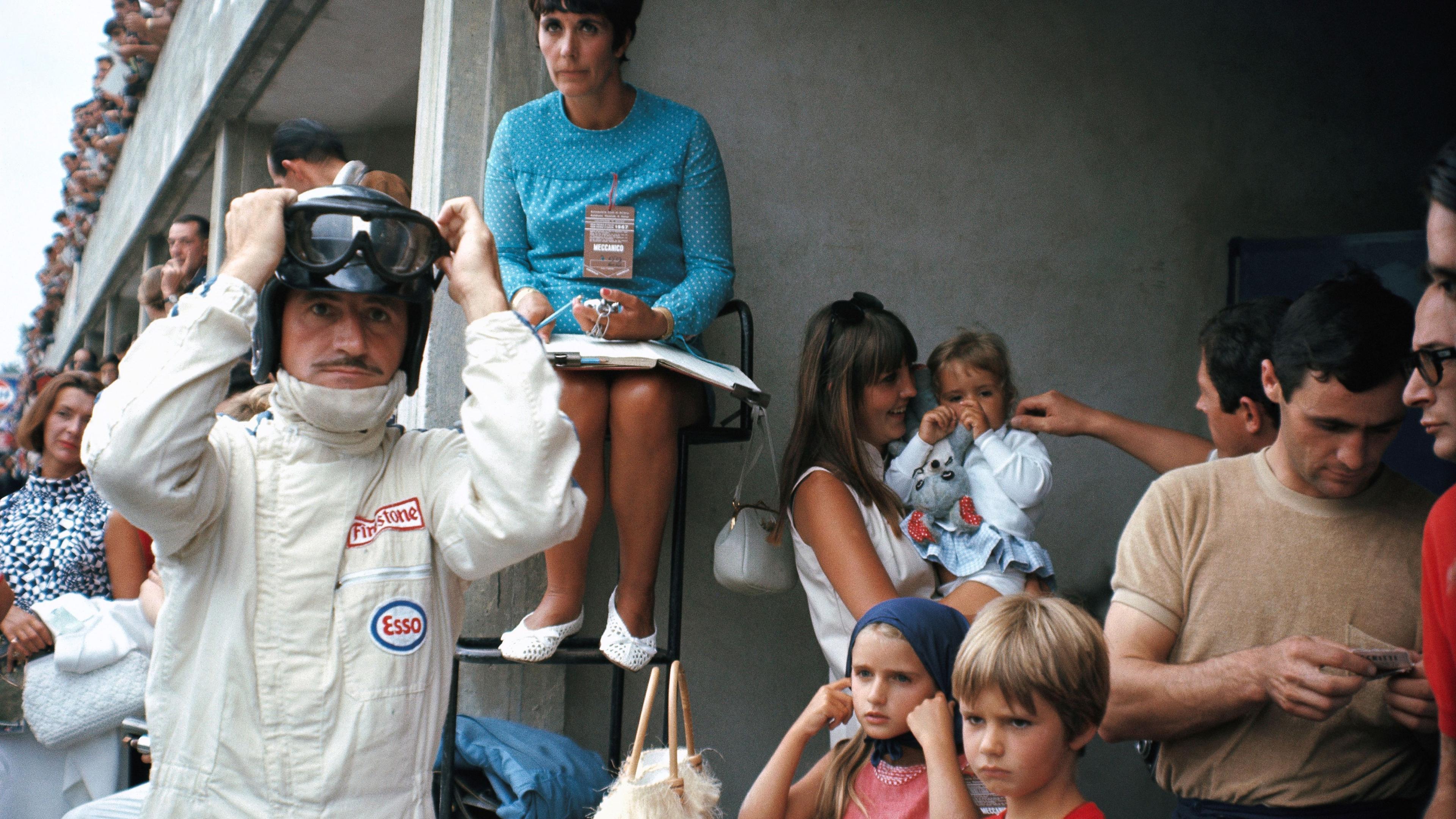 Image caption,Lotus' Graham Hill adjusts his race helmet and visor in the pits before the 1967 race. Gathered around the Englishman is his family, including wife Bette and his children. The 1996 world champion Damon Hill, six years old when this picture was taken, is standing at the front.