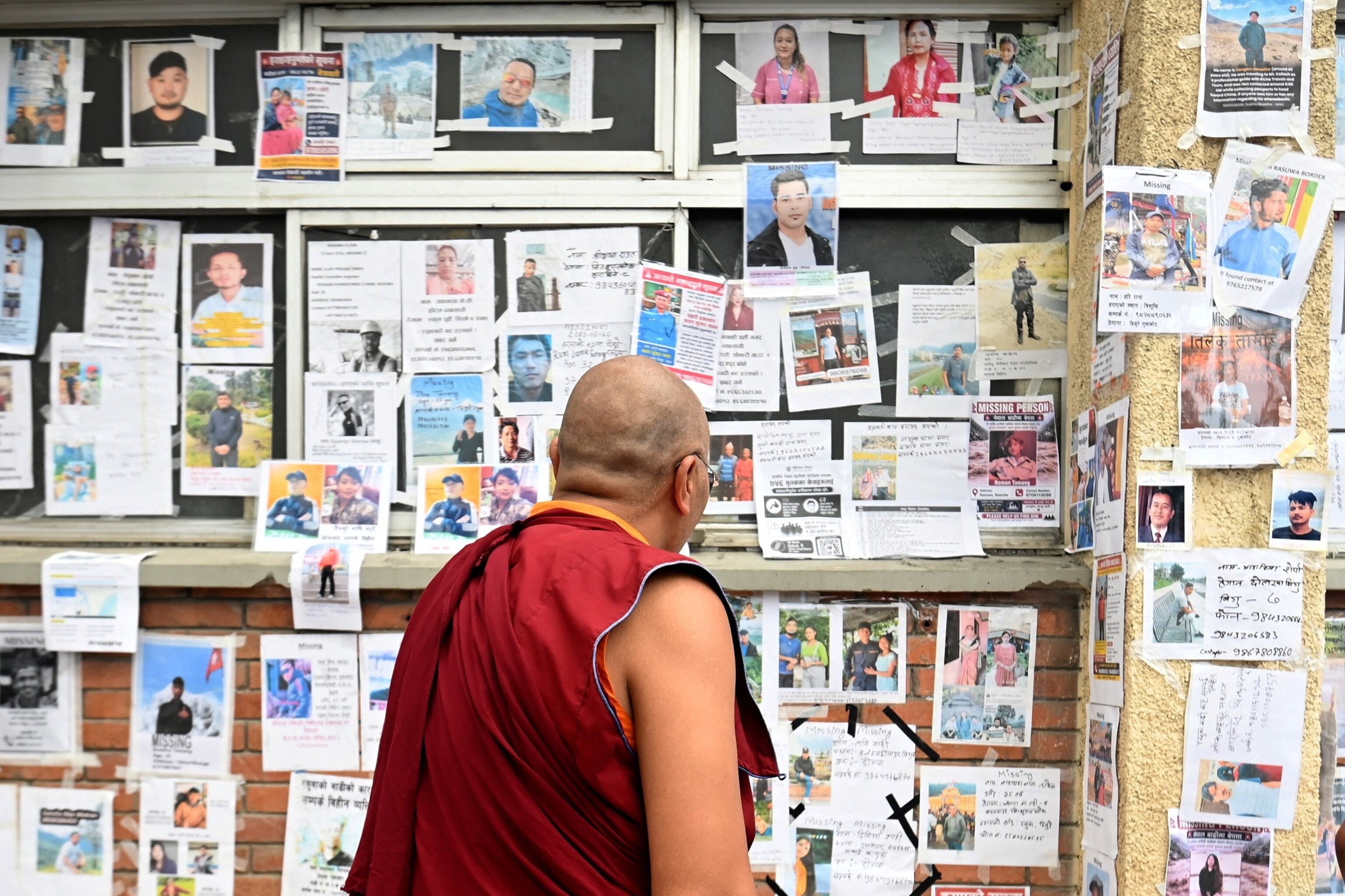 A Buddhist monk looks at photographs of missing and deceased people pasted on wall outside Tribhuvan University Teaching Hospital, following flash floods and a mudslide, in Kathmandu, Nepal, September 1, 2026.Monika Malla/Reuters