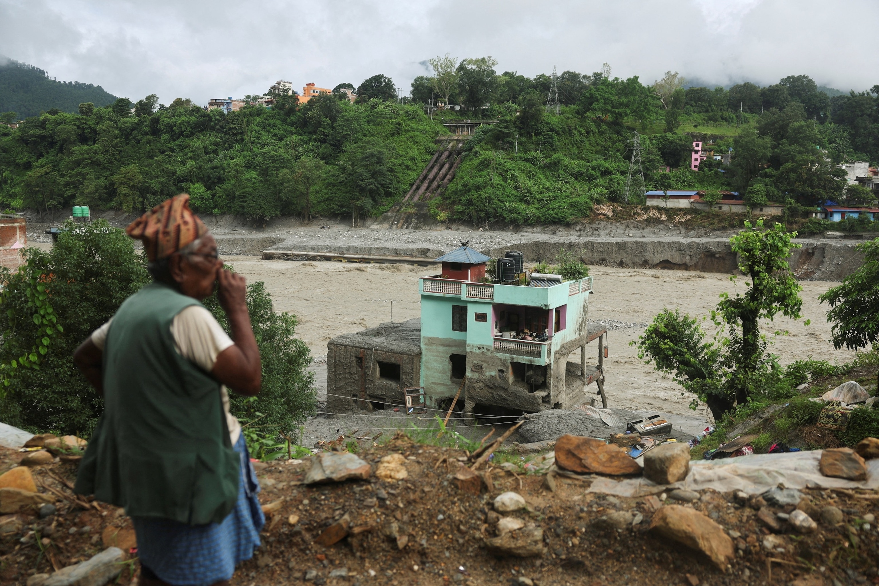 A man looks at the "green miracle house" as it stands amid debris after surviving flash floods and a mudslide in Trishuli, Nuwakot district, Nepal, September 1, 2026.Francis Mascarenhas/Reuters