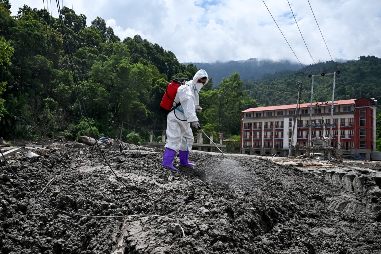 A health worker sprays disinfectant following flash floods in Devighat on Monday.Arun Sankar / AFP via Getty Images