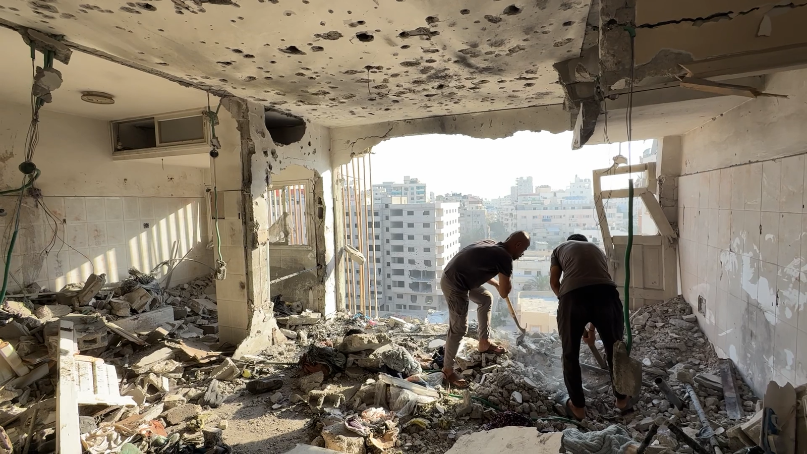 Image caption,Men assess scene of Israeli strike on high-rise block in Gaza City on 2 August