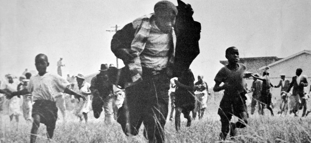 Image caption,The photographer Ian Berry later told the BBC that it seemed the man in the centre of this picture was holding his jacket up "as though to protect himself from the bullets"