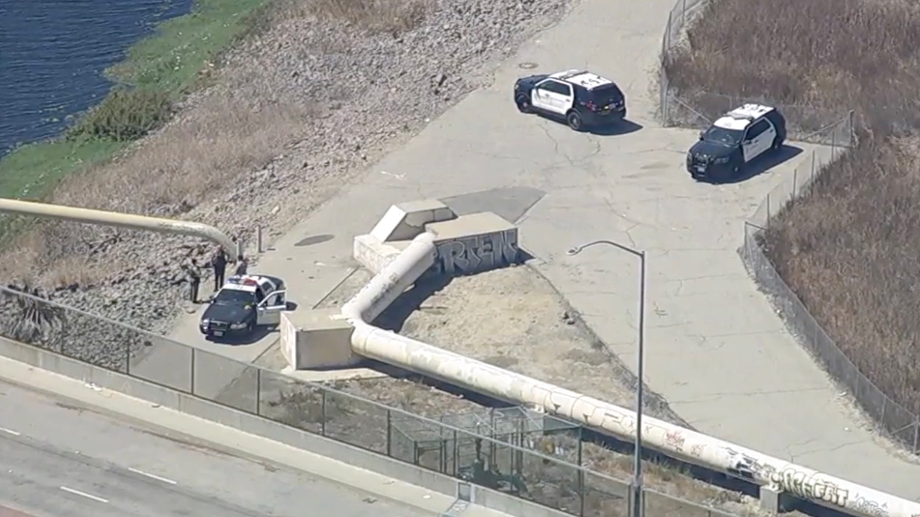 In this screen grab from a video, law enforcement officers are shown at the scene where two bodies were found along the Dominguez Channel in Carson, Calif., on Sept. 1, 2026.KABC