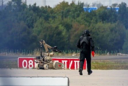 A police officer in protective clothing walks next to an explosive-disarming robot (EOD) at Leipzig airport after a drone was found near a runway last month.Photograph: Axel Schmidt/Reuters