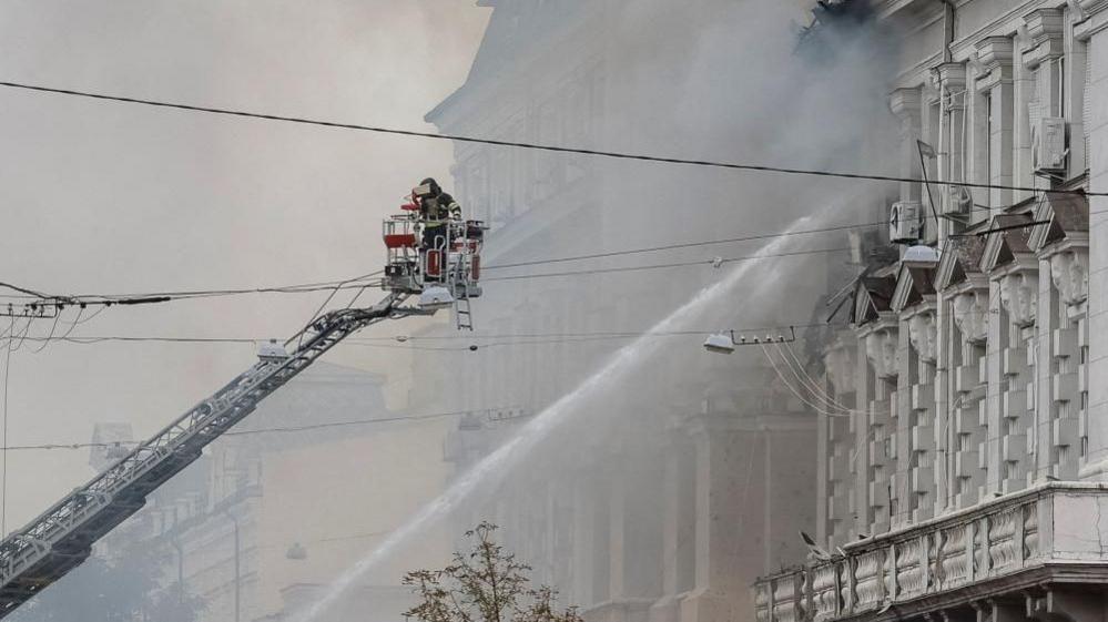 Image caption,Firefighters work to put out fires in the building following the Russian drone strike