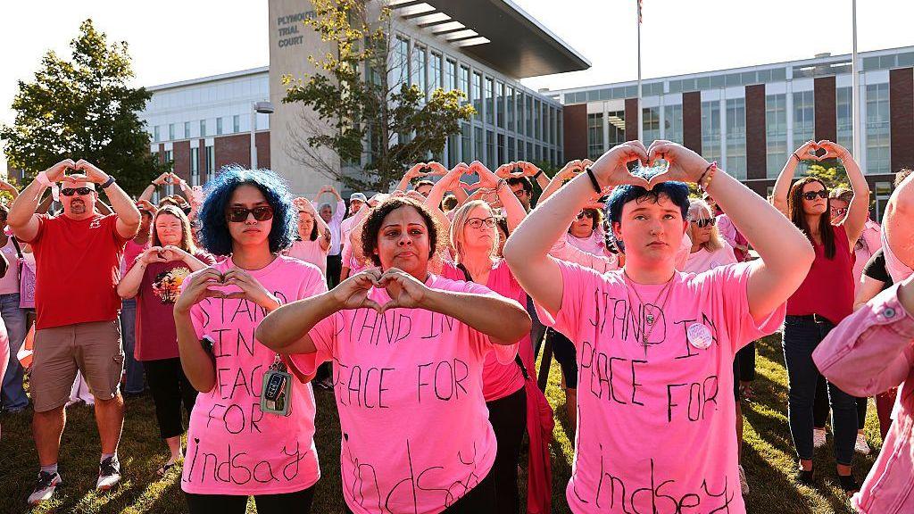 Image caption,Clancy supporters - many wearing pink - huddled outside the courthouse