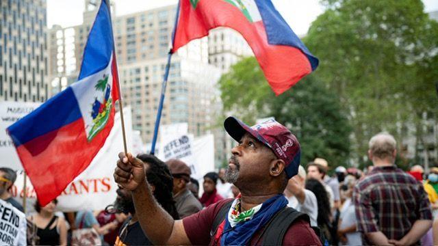 Image caption,An activist waves a Haitian flag in New York during an August march in support of Temporary Protected Status for Haitians