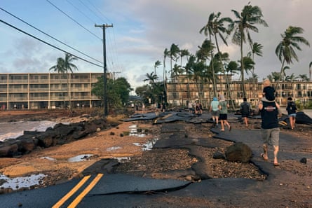 People walk past damage caused by Hurricane Lowell in Poʻipū on Kauaʻi’s south shore, in Hawaii.Photograph: Guy Miller/Honolulu Civil Beat via AP