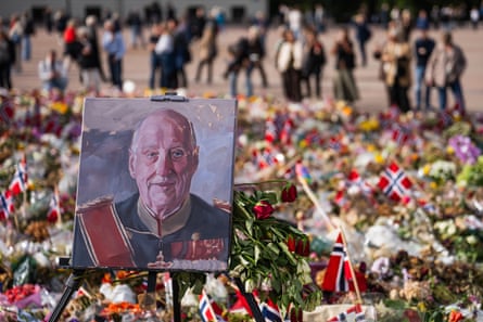 A painted portrait of Norway’s King Harald V is displayed among flowers and Norwegian flags at a makeshift memorial outside the royal palace in Oslo.Photograph: Jonathan Nackstrand/AFP/Getty Images